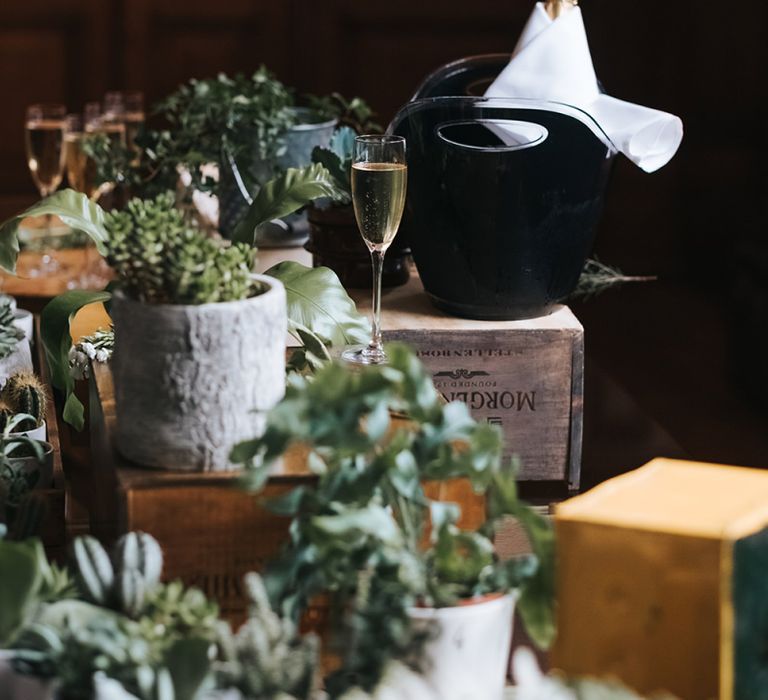 Champagne Table Decorated with Succulents and Wooden Crates | Wedding Reception at Town Hall Hotel | Statement Floral Arrangement Altar and Potted Plants with Copper Frame Table Plan and Lace Jacket | Miss Gen Photography