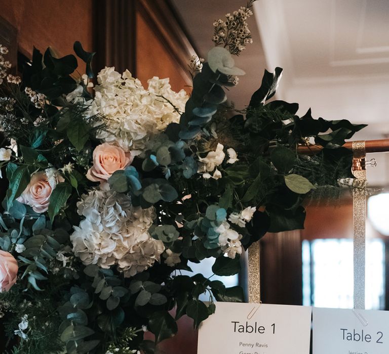 Copper Frame Table Plan | Gold Ribbon | Floral Arrangement of White Hydrangeas, Blush Roses and Foliage | Statement Floral Arrangement Altar and Potted Plants with Copper Frame Table Plan and Lace Jacket | Miss Gen Photography