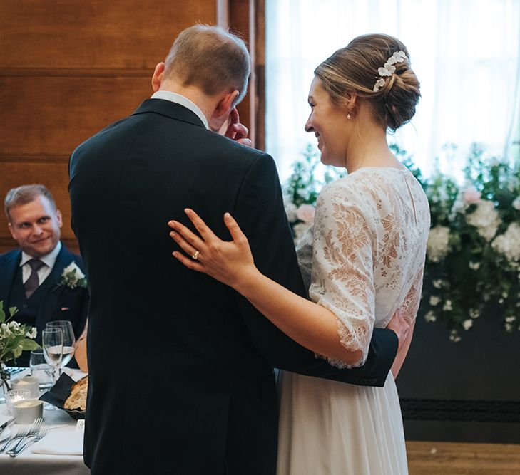 Bride in Charlie Brear Carenne Dress with Spaghetti Straps and Flowing Skirt | Bridal Lace Jacket by Charlie Brear | Porcelain Floral Hairpiece by Eden B | Groom in Navy Three-Piece Suit with Blush Pocket Square | Wedding Reception at Town Hall Hotel | Statement Floral Arrangement Altar and Potted Plants with Copper Frame Table Plan and Lace Jacket | Miss Gen Photography