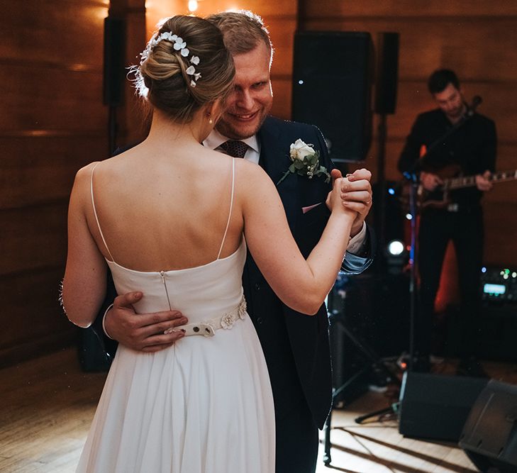 Bride in Charlie Brear Carenne Dress with Spaghetti Straps, Flowing Skirt and Flower Belt | Porcelain Floral Hairpiece by Eden B | Groom in Navy Three-Piece Suit with Blush Pocket Square | First Dance at Town Hall Hotel | Statement Floral Arrangement Altar and Potted Plants with Copper Frame Table Plan and Lace Jacket | Miss Gen Photography