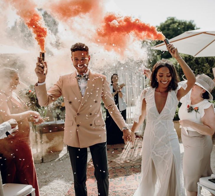 Boho bride and groom holding orange smoke bombs