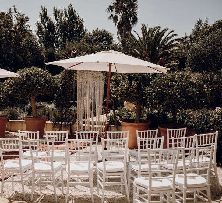 Outdoor wedding ceremony with parasols and macrame backdrop