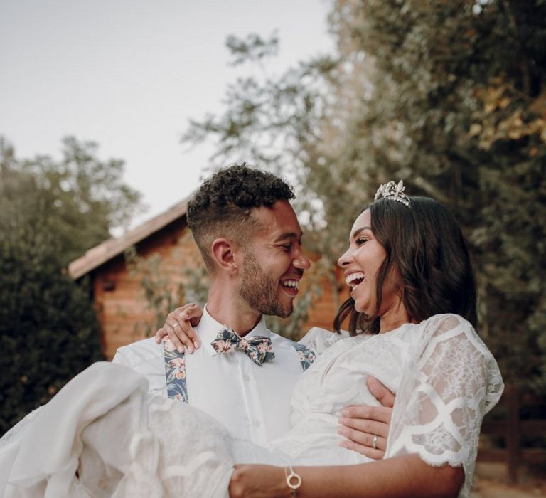 Groom sweeping his bride off her feet in a Grace Loves Lace dress