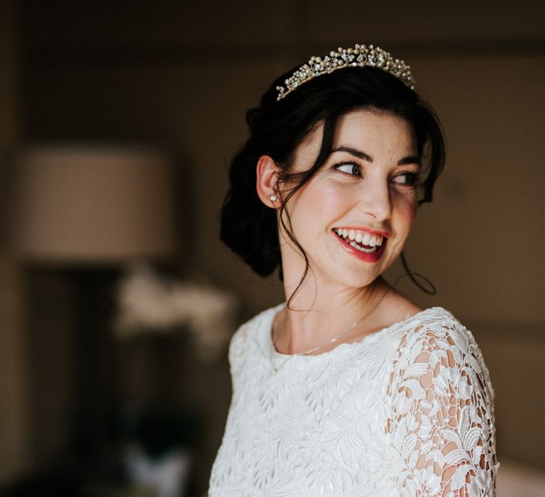 Bride turns and looks at herself in the mirror as she holds a small bottle of perfume