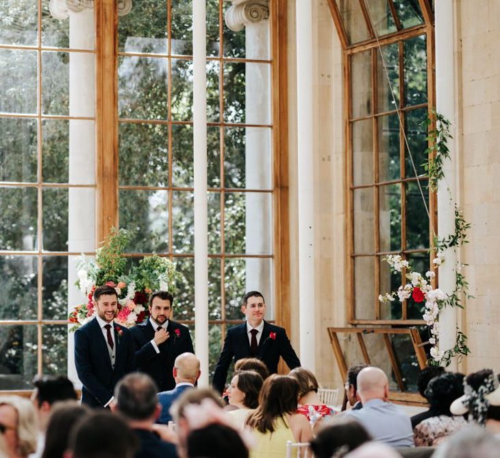 Groom and two gromsmen stand at the front of the aisle at Nash Conservatory in Kew Gardens wedding waiting for the bride to arrive