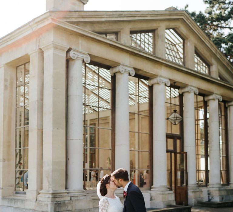 Bride and groom kiss outside of Nash Conservatory at Kew Gardens