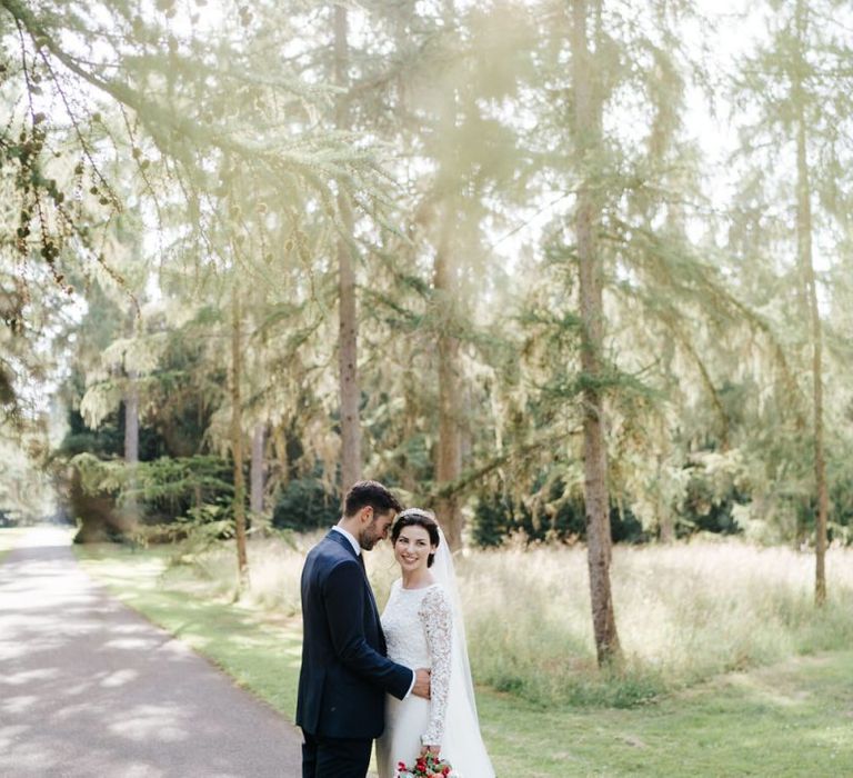 Bride and groom stand in beautiful light in Woodlands area in Kew Gardens and pose for a photograph