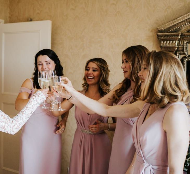 Bride and bridesmaids clinck glasses and cheer