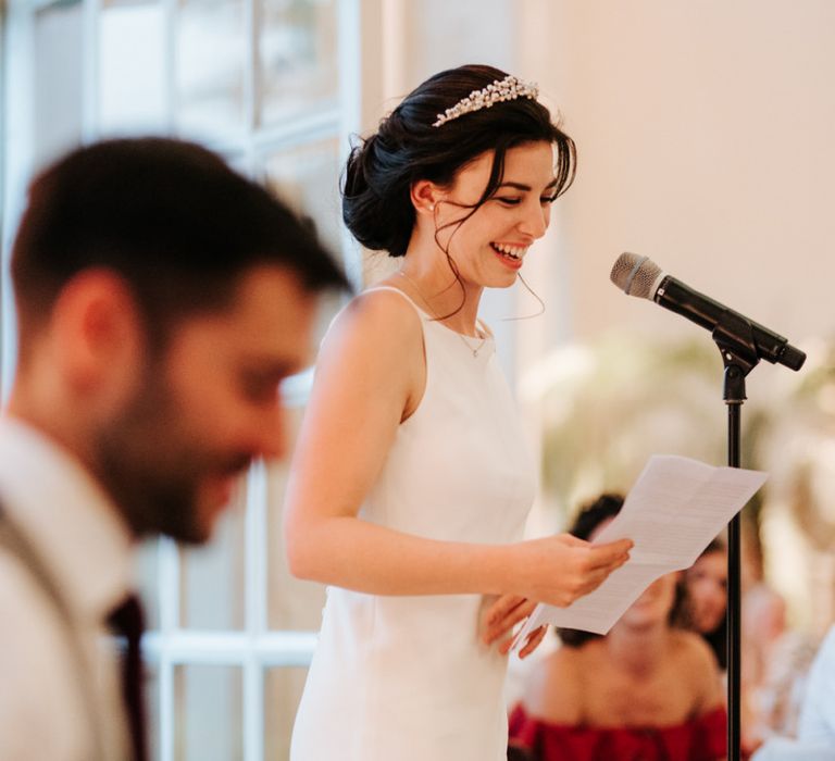 Bride stands and smiles as she delivers her wedding speech