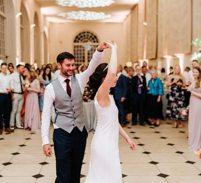 Bride and groom have their first dance as guests look on