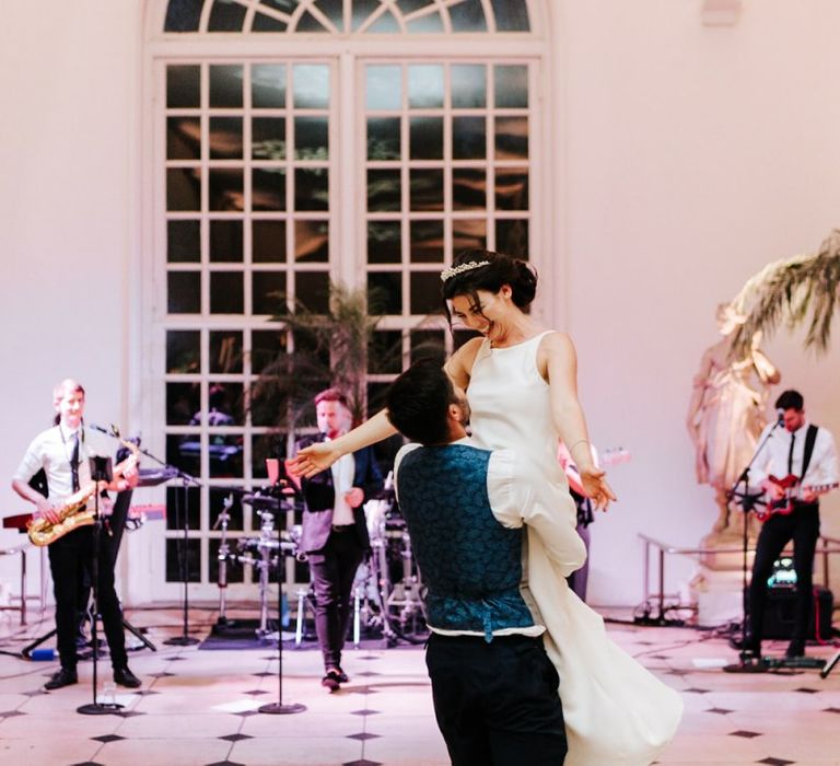 Groom lifts bride up and swings her around during first dance at Kew Gardens Nash Conservatory Wedding