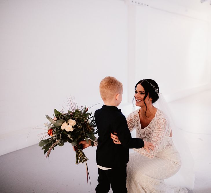 Bride in Lenora Dress by Wtoo Watters with Lace Sleeves and Keyhole Back | Prudence Halo Headpiece by Kelly Spence Wed | Floor Length Veil | Burgundy, Blush and White Flowers with Foliage and Ferns | Groom in Navy Suit with Grey Waistcoat from Jack Bunneys | String Lights, Perspex Table Signs and Paper Cranes for Industrial Wedding | Frankee Victoria Photography