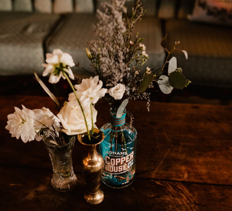 Foliage and Pampas Grass in Gin Bottle | White Flowers in Gold Vase | Trinity Buoy Wharf Wedding Venue | String Lights, Perspex Table Signs and Paper Cranes for Industrial Wedding | Frankee Victoria Photography