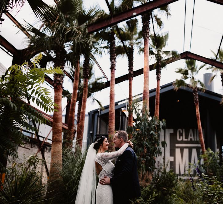 Bride in Lenora Dress by Wtoo Watters with Lace Sleeves and Keyhole Back | Prudence Halo Headpiece by Kelly Spence Wed | Floor Length Veil | Groom in Navy Suit with Grey Waistcoat from Jack Bunneys | String Lights, Perspex Table Signs and Paper Cranes for Industrial Wedding | Frankee Victoria Photography