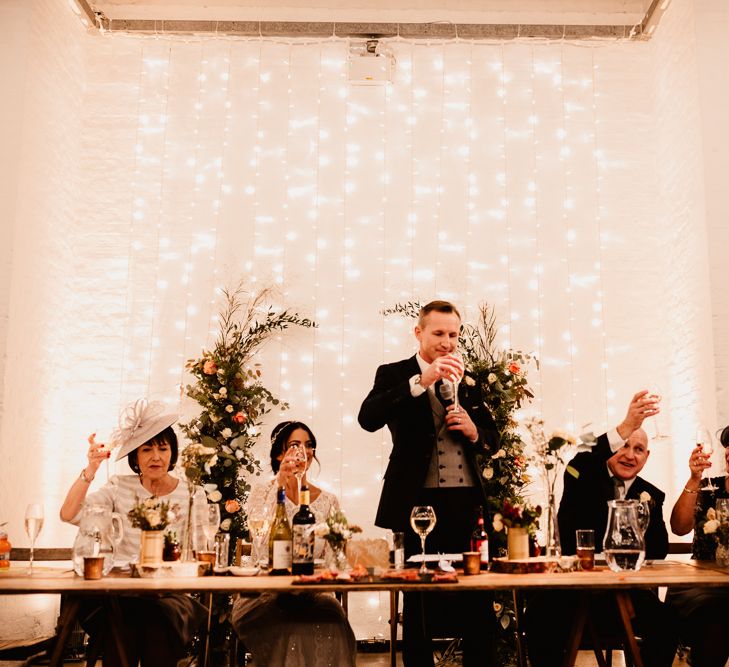 Groom in Navy Suit with Grey Waistcoat from Jack Bunneys | Bride in Lenora Dress by Wtoo Watters with Lace Sleeves and Keyhole Back | Prudence Halo Headpiece by Kelly Spence Wed | Fairy Light Canopy | Trinity Buoy Wharf Wedding Venue | String Lights, Perspex Table Signs and Paper Cranes for Industrial Wedding | Frankee Victoria Photography