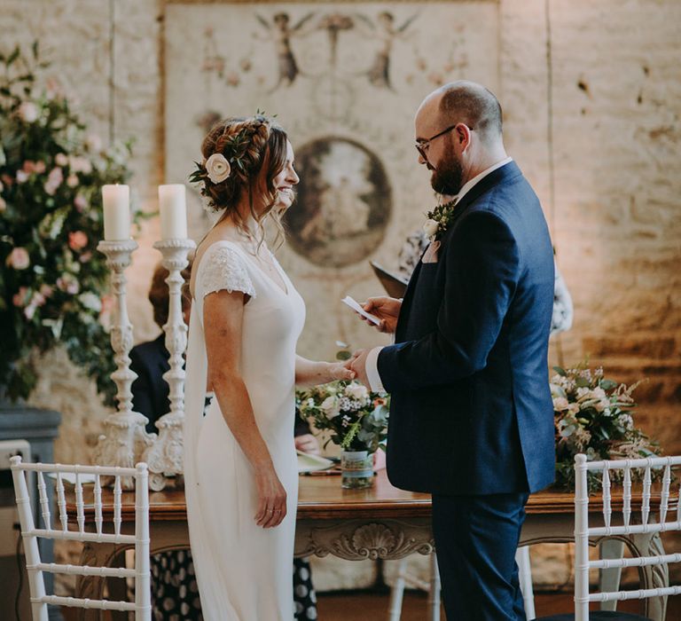 Bride in Pronovias Dralan Wedding Dress  and Groom in Navy Blue Moss Bros.  Suit Exchanging Vows During Wedding Ceremony