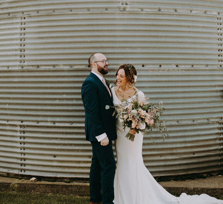 Bride in Pronovias Dralan Wedding Dress and Groom in Navy Moss Bros. Suit Laughing