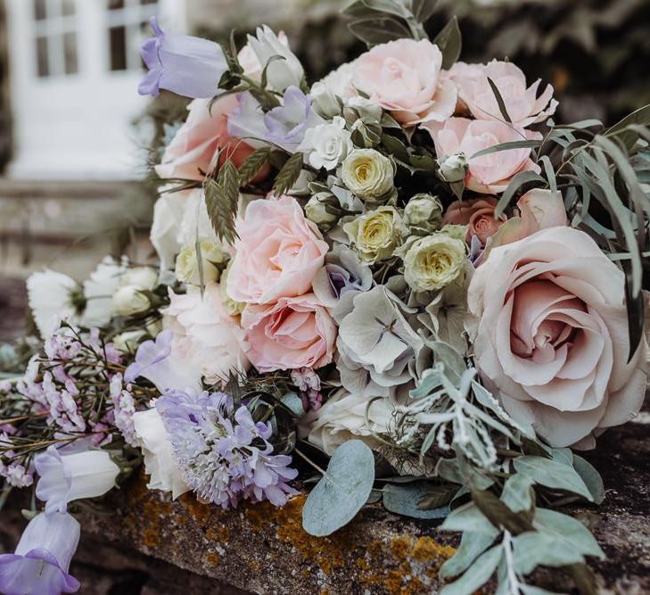 Pastel floral bridal bouquet at rustic barn wedding made up of roses and eucalyptus