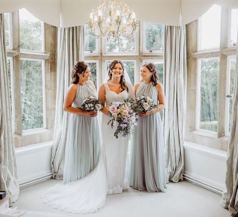 Bride and her bridesmaids clutching pastel floral bouquets at Cogges Manor Farm wedding