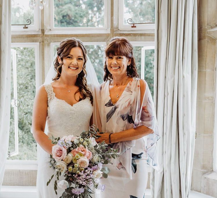 Bride wearing beautiful lace embellished dress with her mother at Cogges Manor Farm wedding