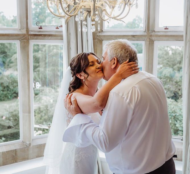 Bride wearing laced bridal dress with long veil and softly curled hair