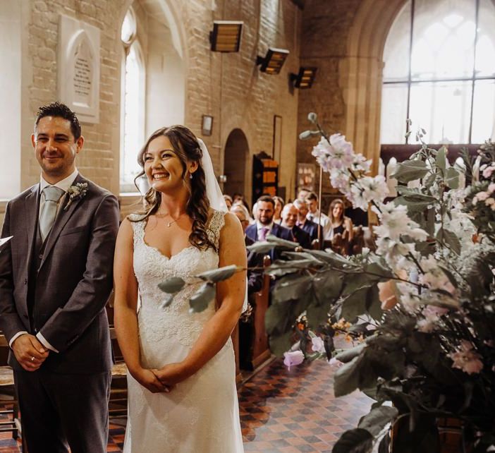 Church wedding ceremony with pastel floral decor and a beautiful laced bridal dress