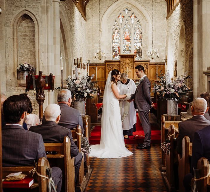 Bride and groom say their vows at intimate church ceremony with pastel floral decor