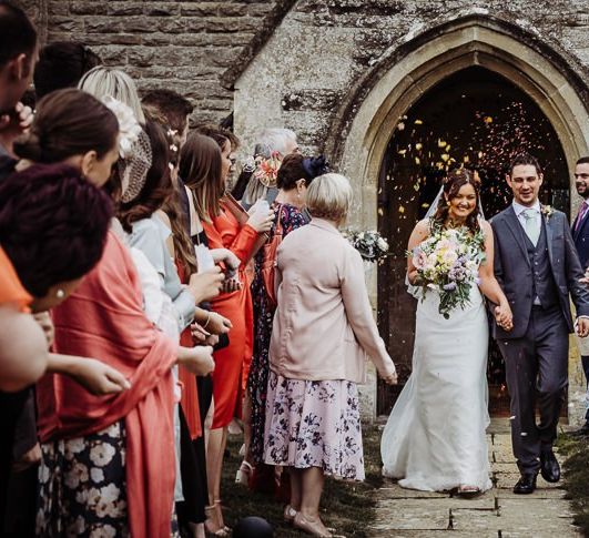 Confetti shot as bride and groom leave the church ceremony holding a beautiful pastel floral bouquet