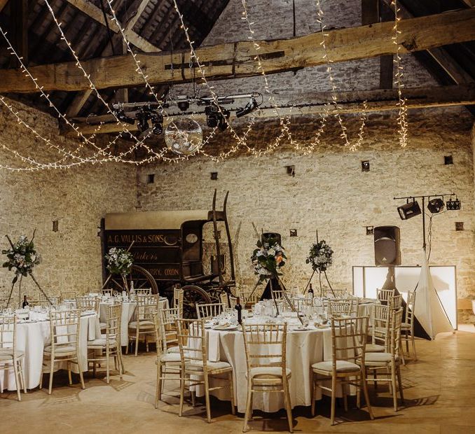 Cogges Manor Farm wedding reception with hanging fairy lights and floral centrepieces