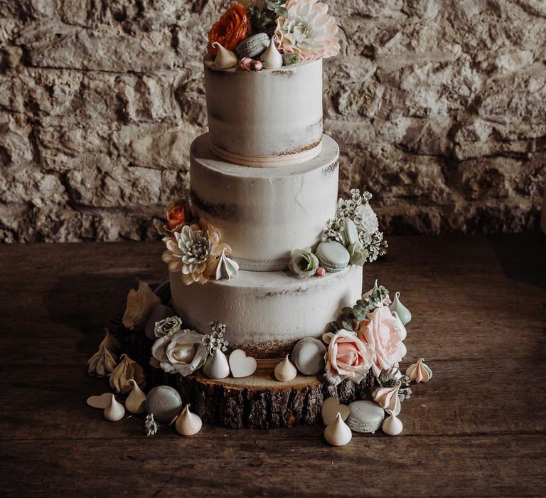 Semi naked wedding cake decorated with florals and macaroons