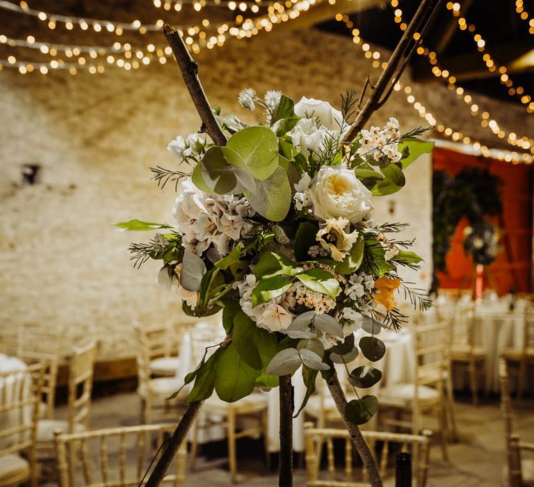 Beautiful floral centrepieces at rustic reception with hanging fairy lights