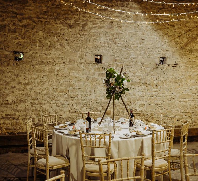 Cogges Manor Farm wedding reception with floral table arrangements and hanging fairy lights