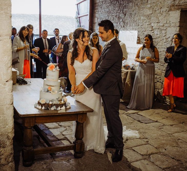 Bride and groom cut their cake at rustic wedding with floral decor