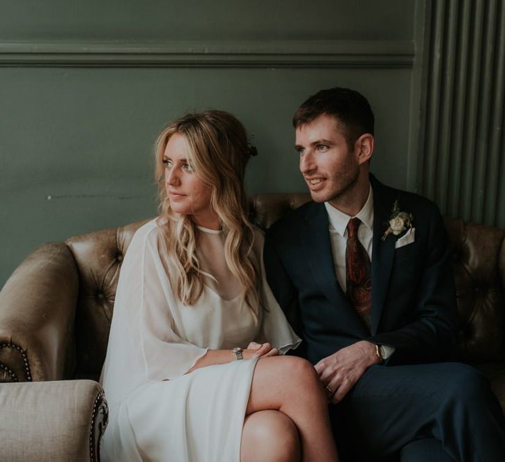 Bride In Wedding Cape Takes a Moment With Husband