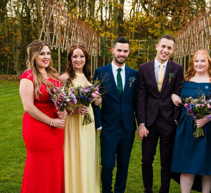 Two Grooms in Burgundy and Navy Remus Uomo Suits and Bridesmaids in Bright Dresses