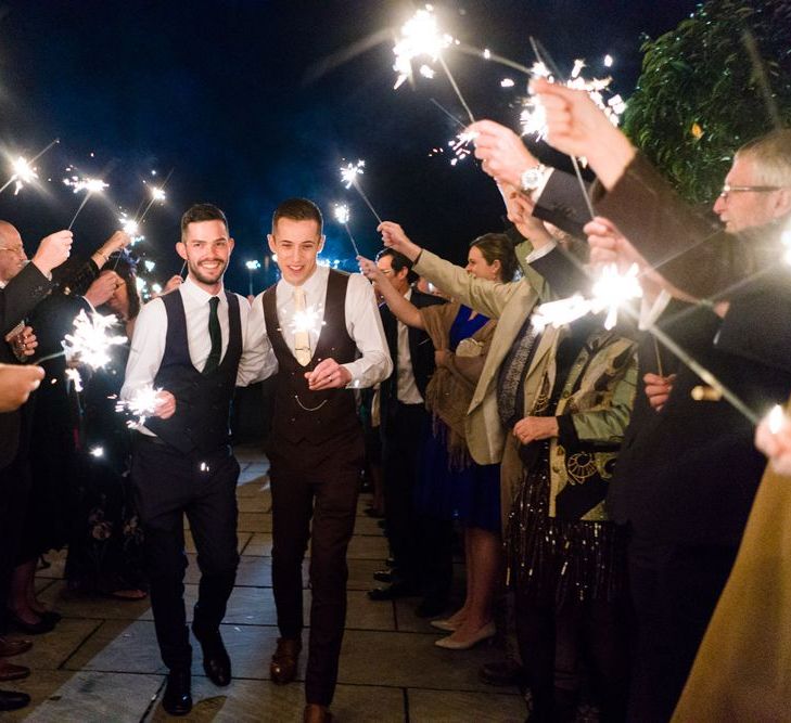 Two Grooms in Burgundy and Navy Remus Uomo Suits during Sparkler Moment