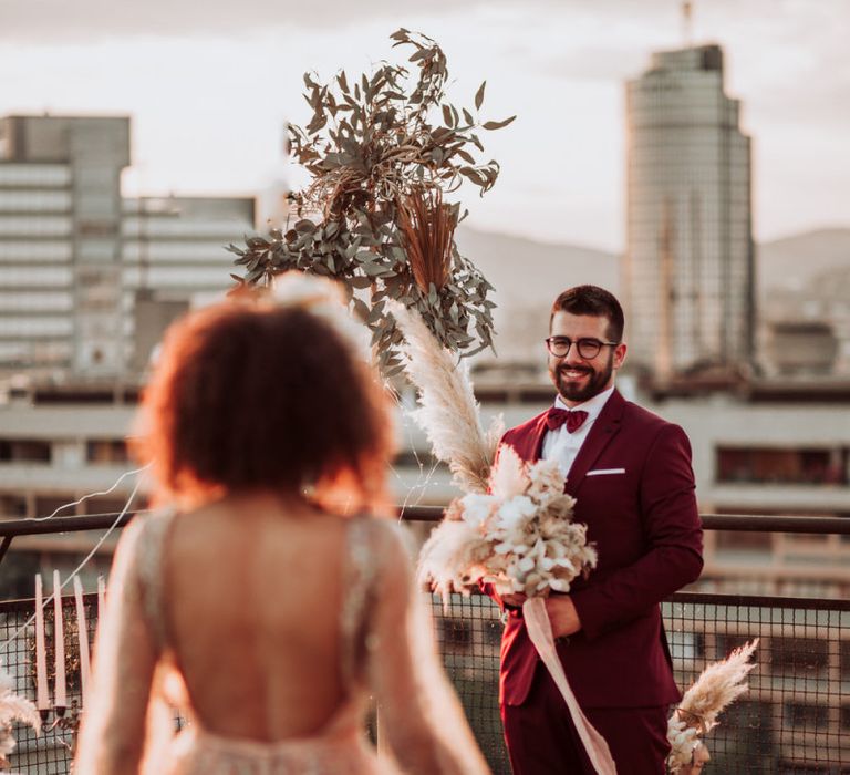 Groom in burgundy suit waiting at the altar