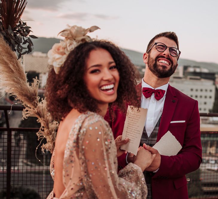 Groom in red suit and bow tie laughing during intimate wedding ceremony