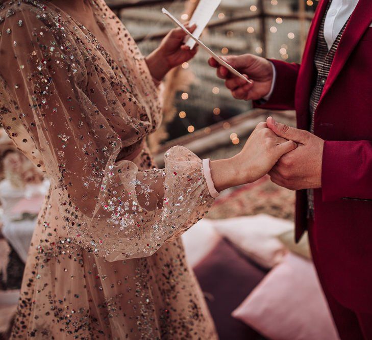 Bride in nude tulle and sparkle wedding dress holding hands with her husband during the wedding ceremony