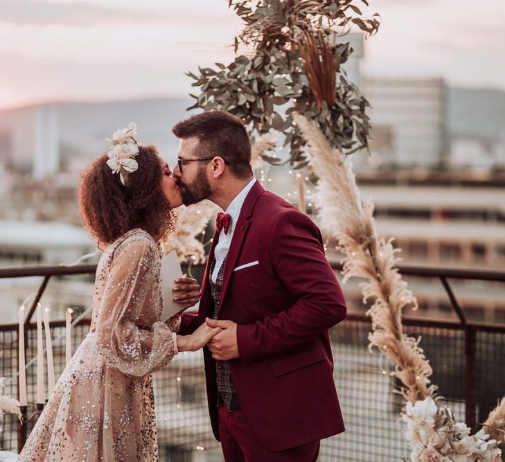 Bride and groom kissing at rooftop wedding