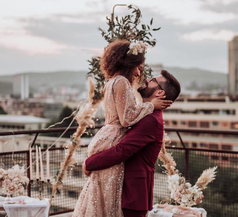 Bride in sparkle wedding dress and groom in burgundy suit at intimate boho wedding