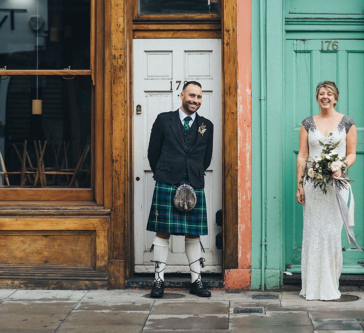 Bride in Embellished Shoulder Sequin Dress with Drop Waist by Eliza Jane Howell | 1920s Style Pearl Draping Headpiece | Bridal Bouquet with White Flowers, Foliage and Grey and Pink Trailing Ribbons | Groom in Green and Blue Tartan Kilt | Metallic Confetti Cannons and Paper Lanterns with Bride in Beaded Shoulder Eliza Jane Howell Dress | Miss Gen Photography