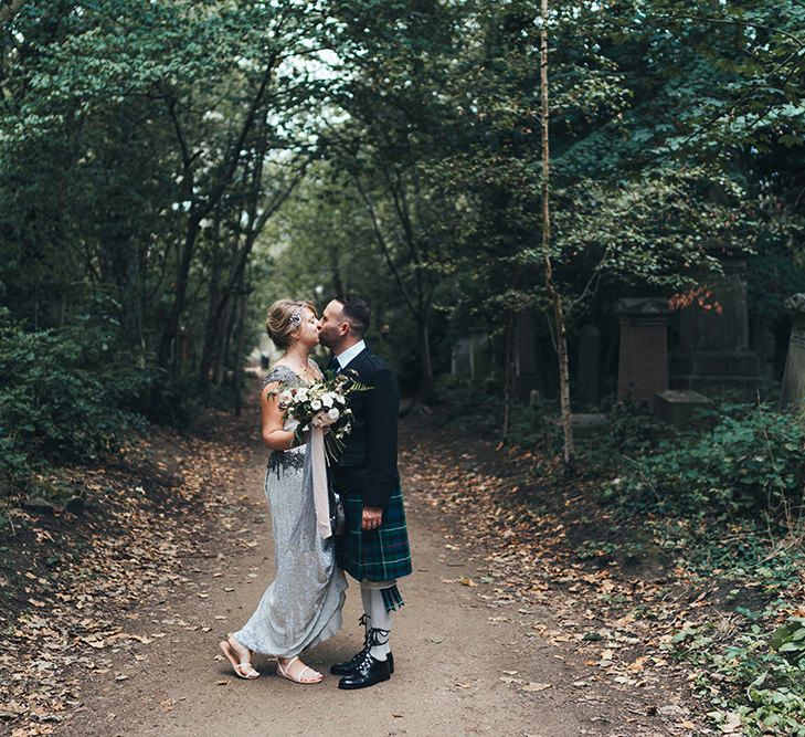 Bride in Embellished Shoulder Sequin Dress with Drop Waist by Eliza Jane Howell | 1920s Style Pearl Draping Headpiece | Bridal Bouquet with White Flowers, Foliage and Grey and Pink Trailing Ribbons | Strappy White Flat Sandals for Bride | Groom in Green and Blue Tartan Kilt | Metallic Confetti Cannons and Paper Lanterns with Bride in Beaded Shoulder Eliza Jane Howell Dress | Miss Gen Photography