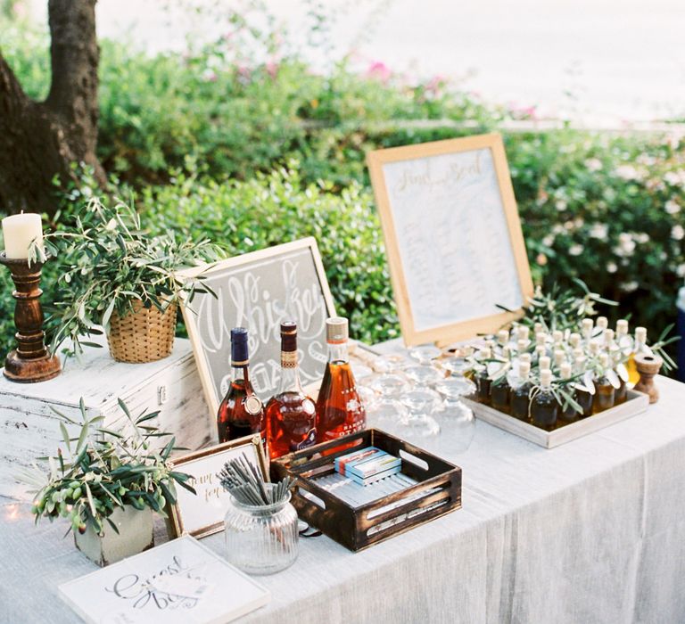 Whiskey &amp; Cigar Bar, Olive Oil Favours and Table Plan Wedding Decor | Pastel Blue &amp; Green, Romantic, Destination Wedding at Corfu Luxury Villas, Planned by Rosmarin Weddings &amp; Events | Mikhail Balygin Fine Art Wedding Photographer