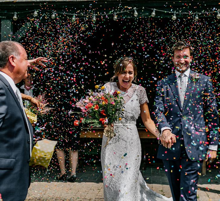 Confetti Exit with Bride in Lace Made with Love Wedding Dress and Groom in Navy Suit