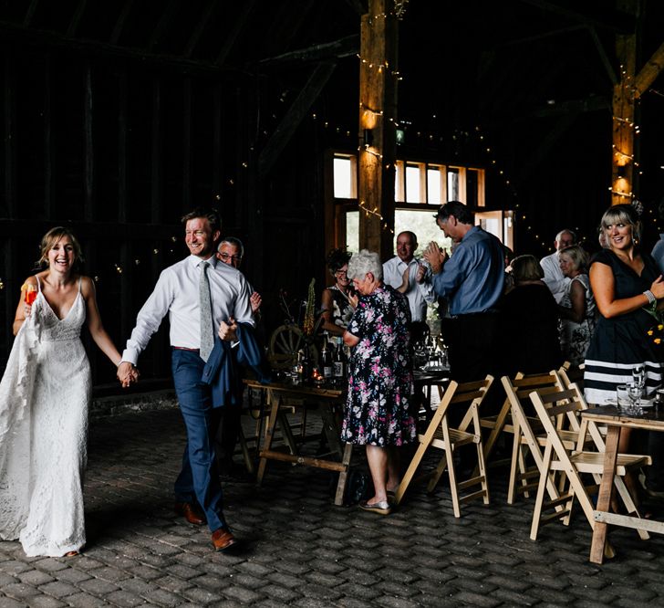 Bride in Made with Love Lace Wedding Dress and Groom in  Godfather Tailoring Entering the Wedding Reception