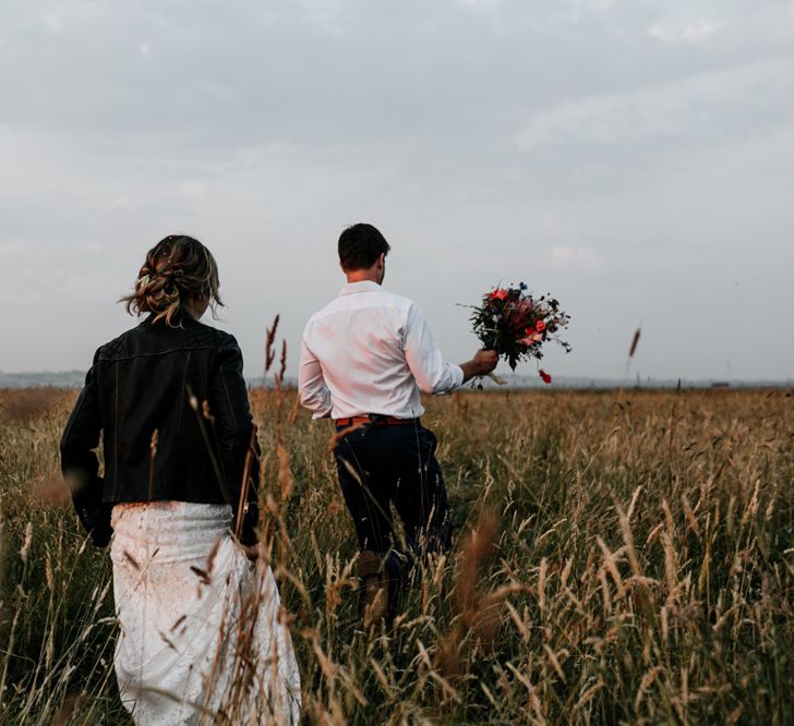 Bride in Made with Love Lace Wedding Dress and Groom in Godfather Tailoring Walking Through Corn Fields