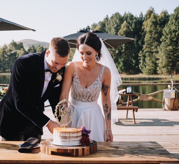 Bride and Groom Cut The Wedding Cake With Cake Topper