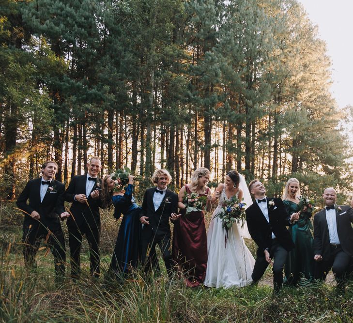 Wedding Party Strikes A Pose In Forest At Cool Wedding With Polaroid Guest Book