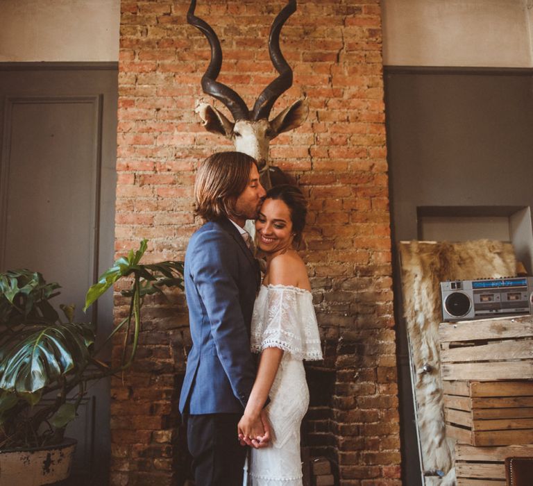 Bride in Off The Shoulder Wedding Dress and Groom in Blue Blazer Holding Hands